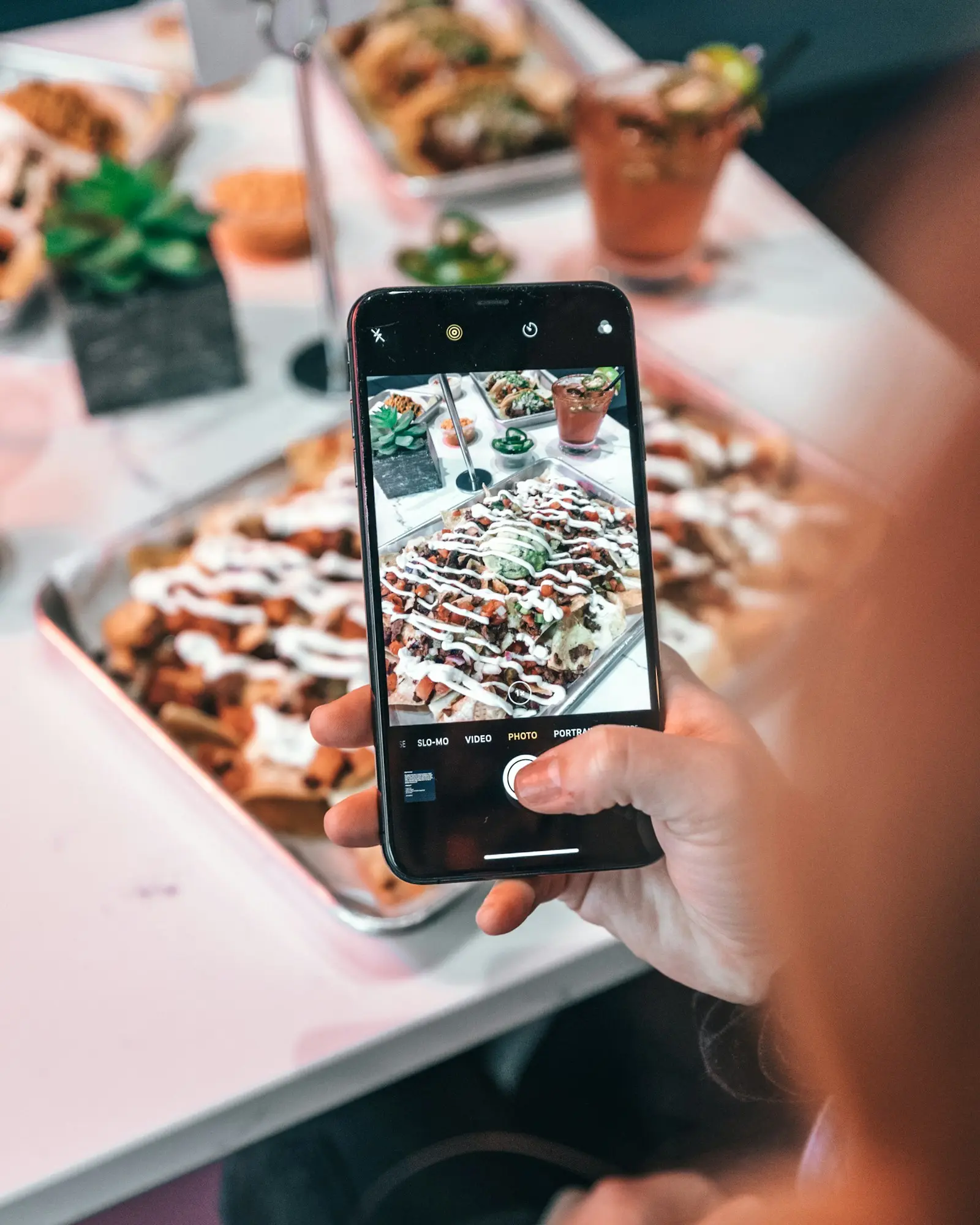 A phone held up to film a tray of loaded fries