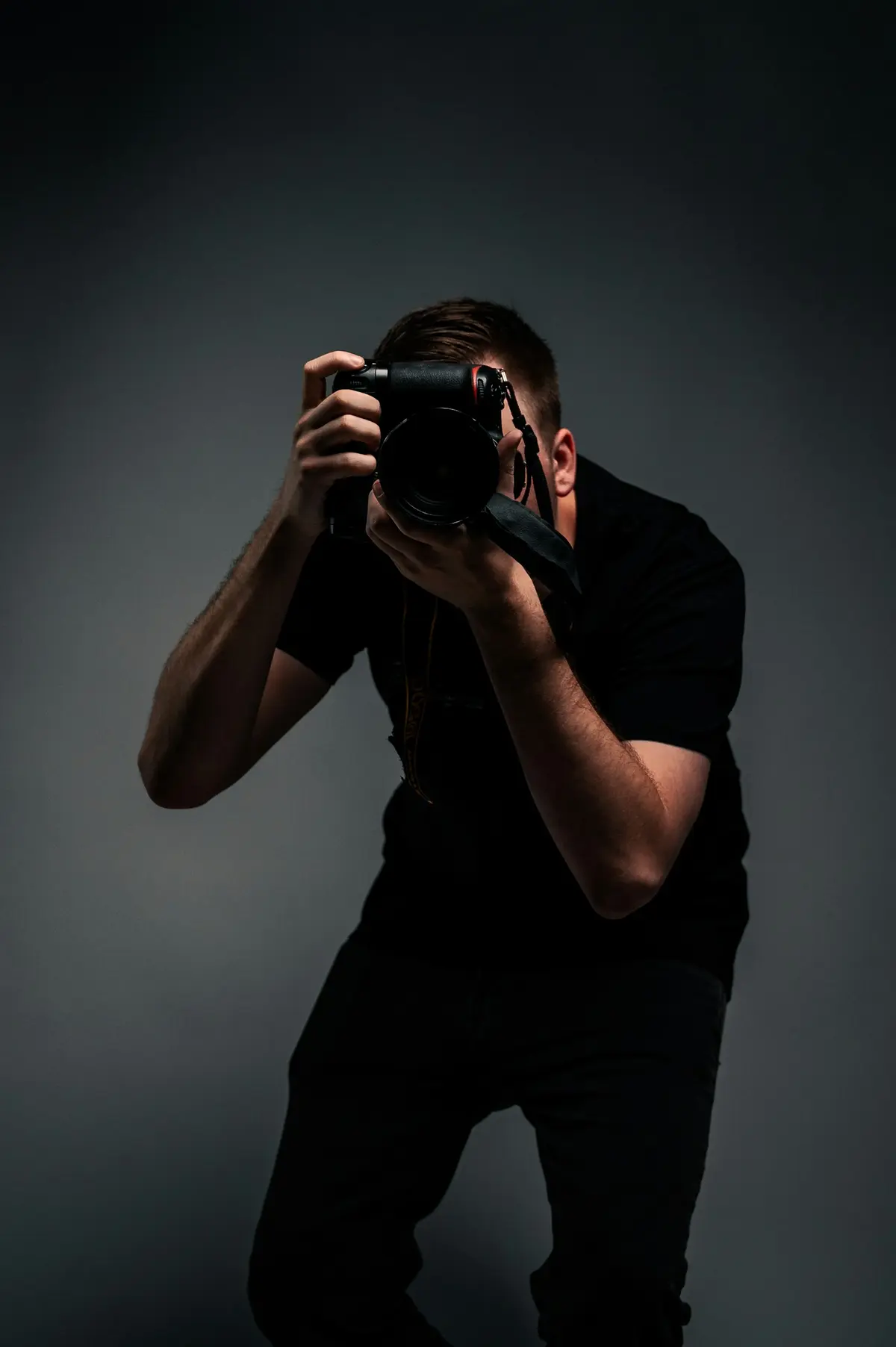 A photographer in a dark studio, camera raised to his eye