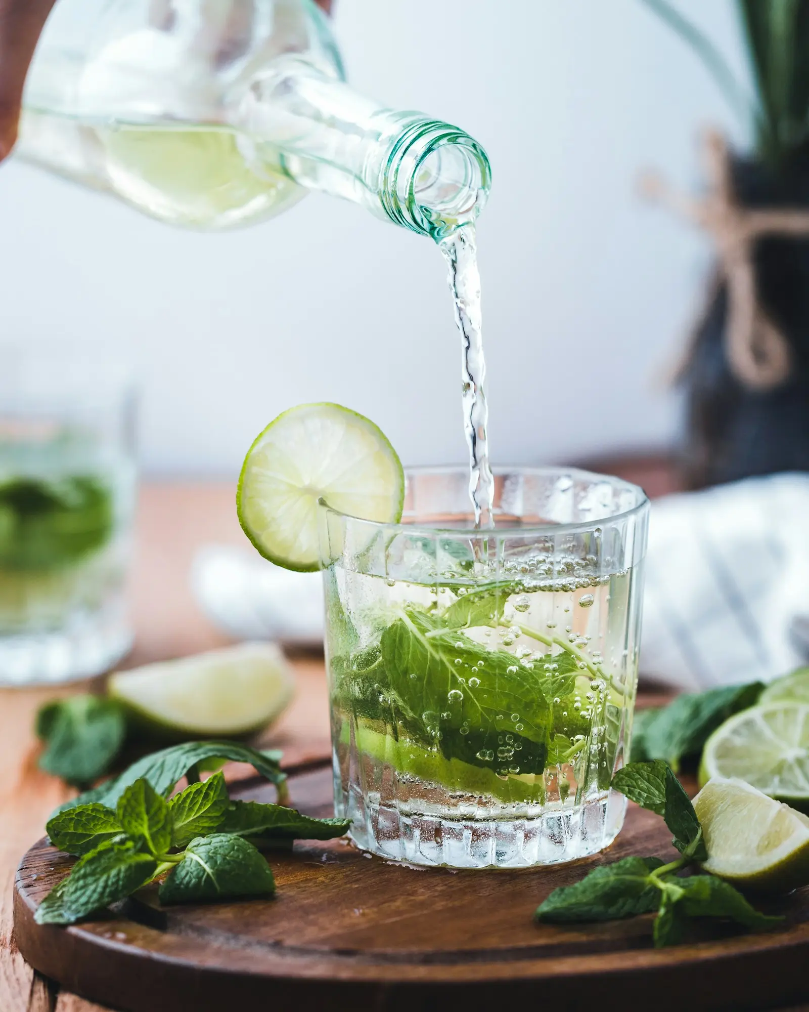 Sparkling water poured into a glass of mint and lime