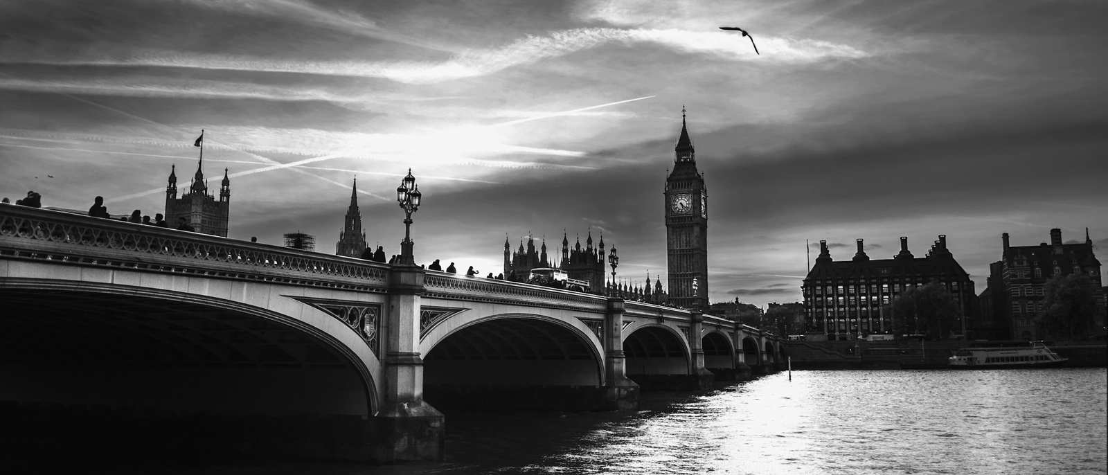 Westminster Bridge and the Houses of Parliament against a dramatic evening sky, in black and white.