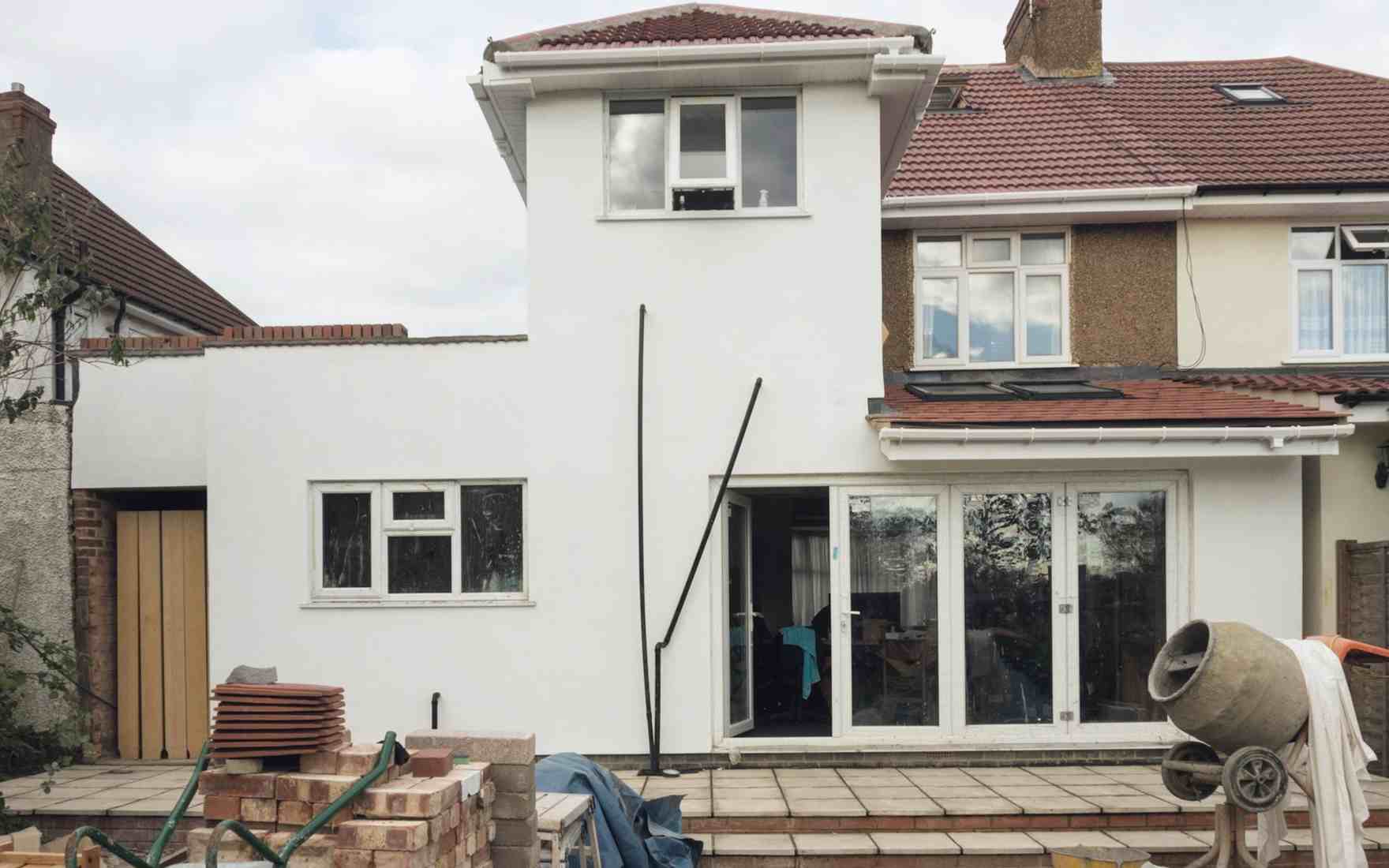 Before: the same house on site in week 11, with bricks, a cement mixer and a wheelbarrow on the patio
