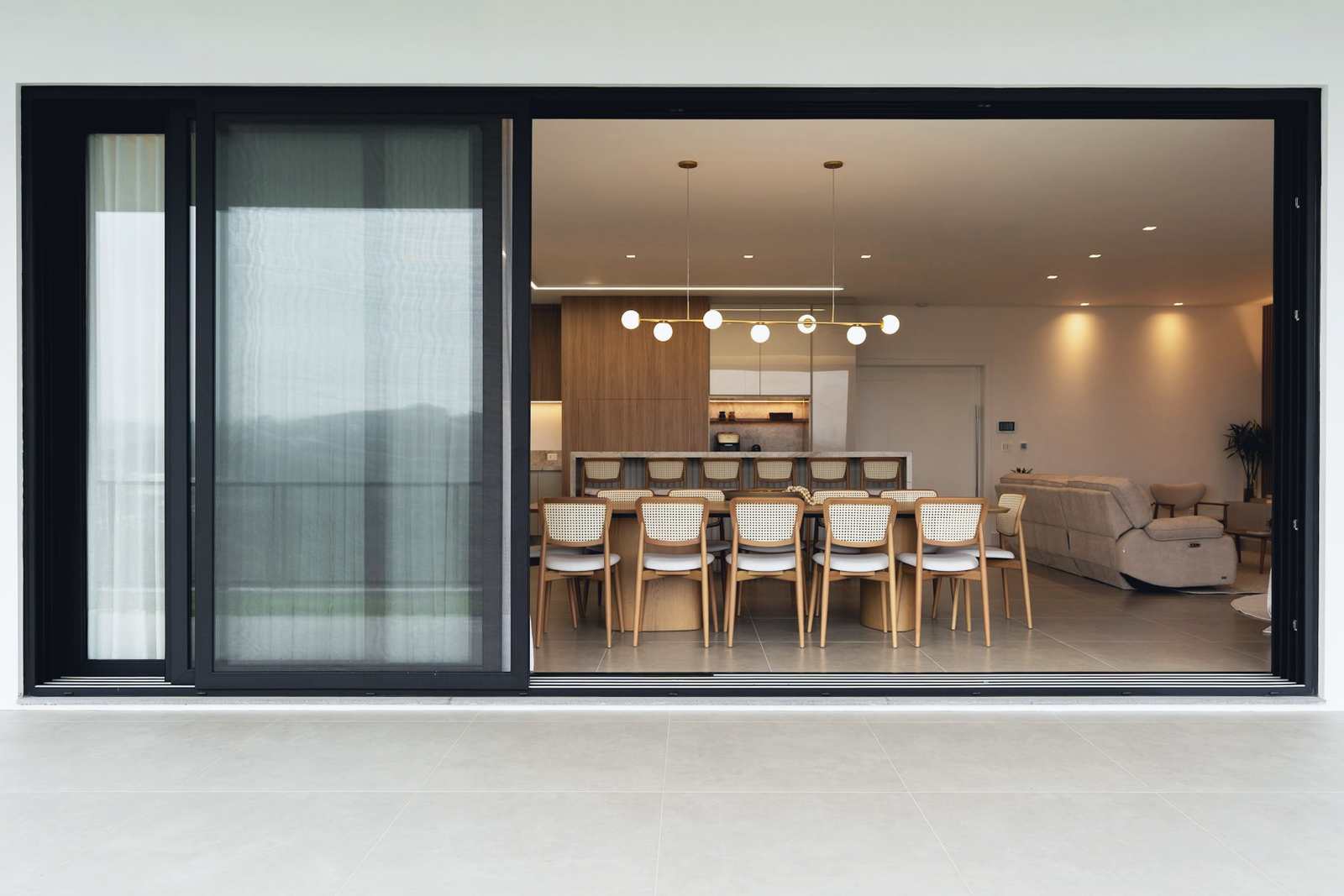 After: the new wraparound kitchen and dining room seen through a wide dark-framed opening