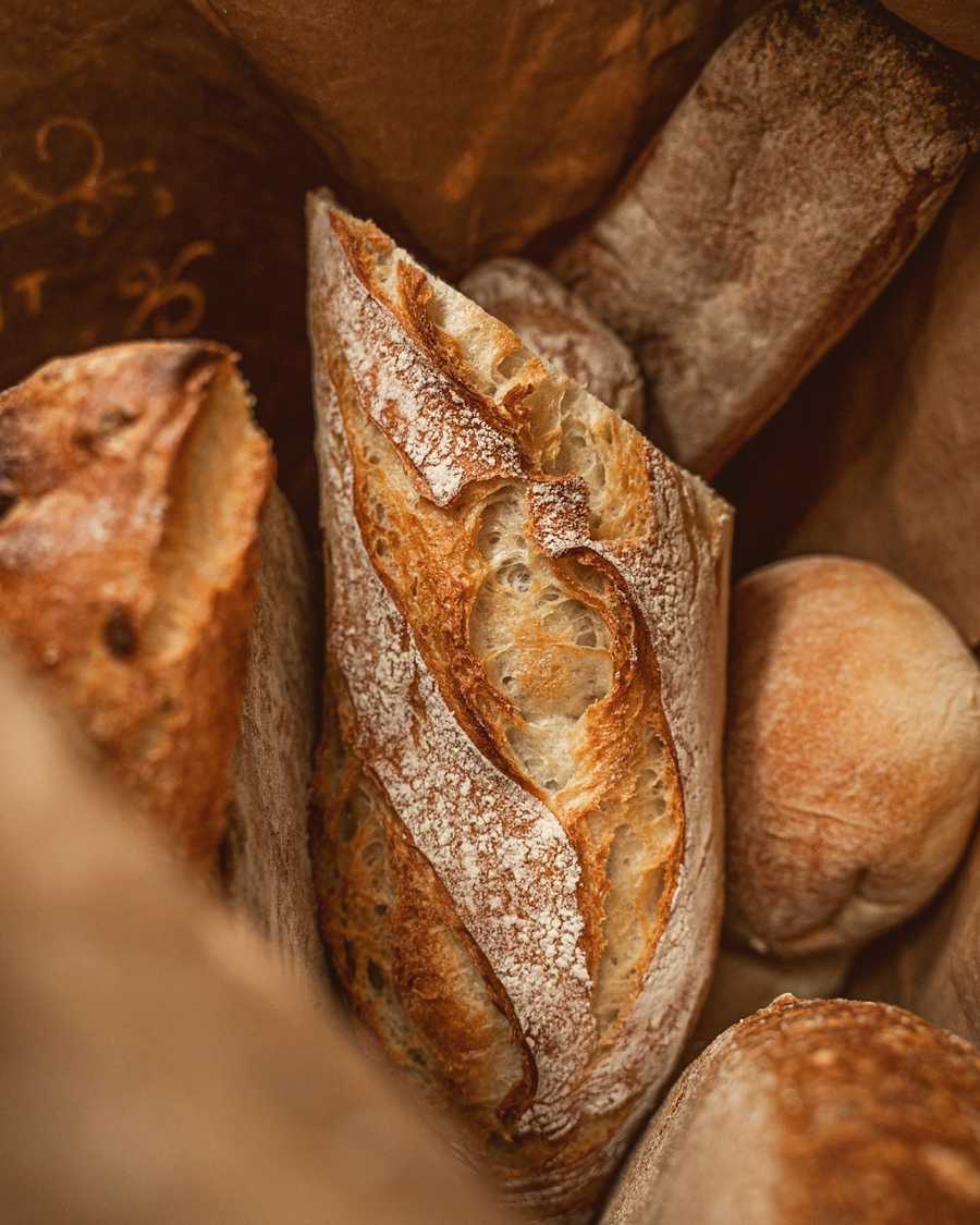 Sourdough loaves and a baguette in a brown paper bag
