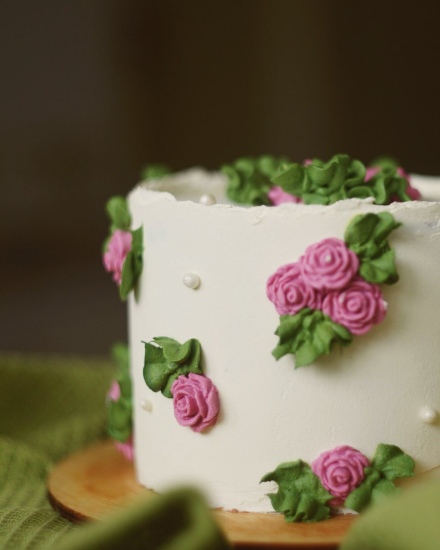 A smooth white cake with piped pink buttercream roses