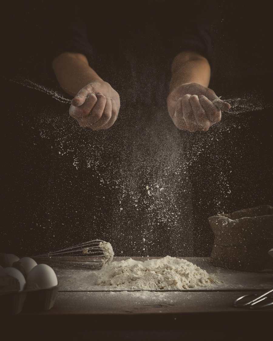 Flour falling through low light onto a dark bench