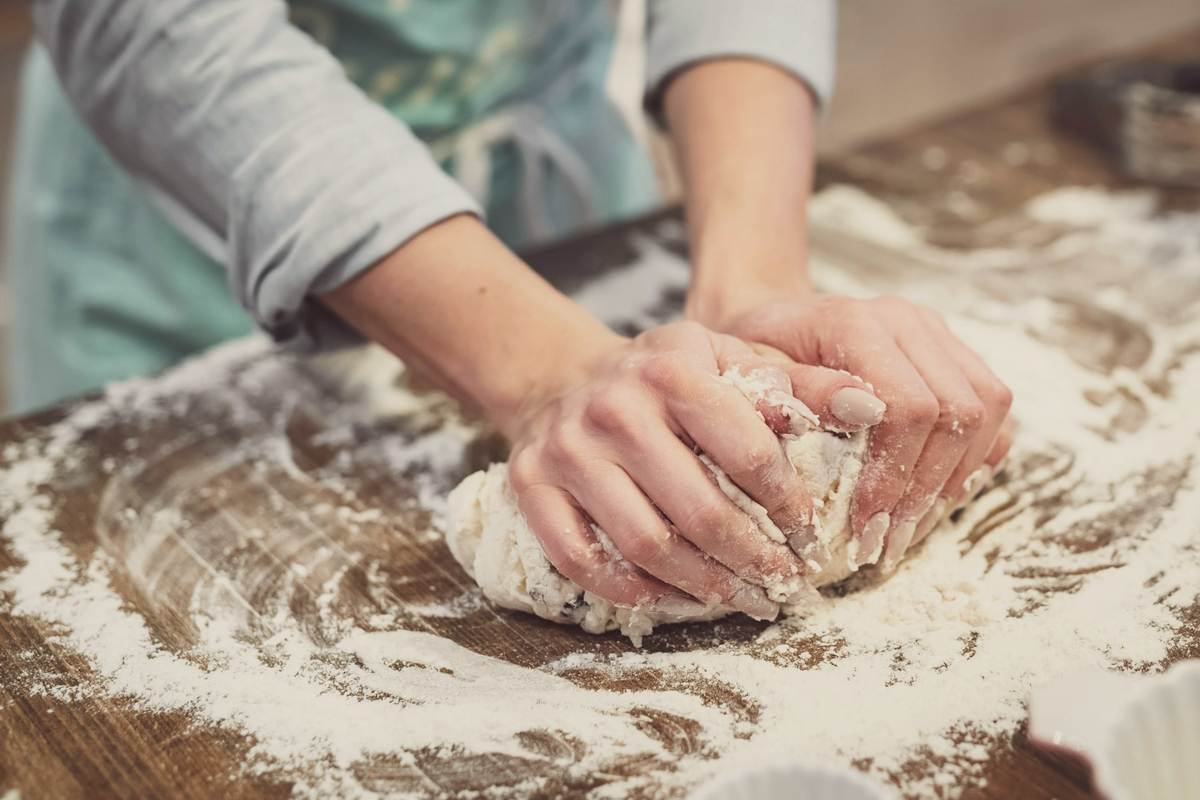 Floury hands kneading dough on a wooden bench