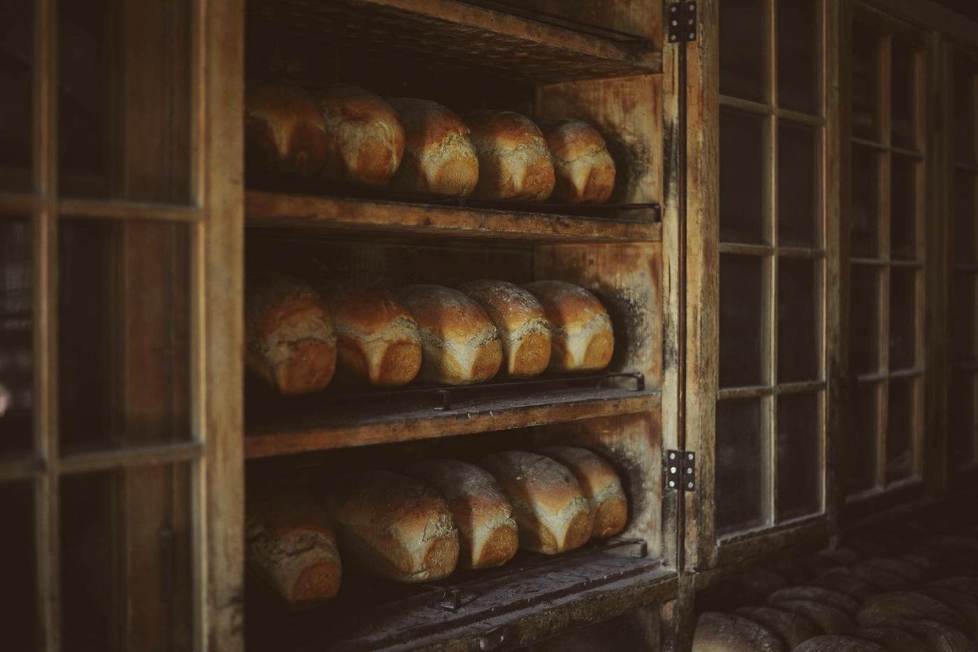 Rows of tin loaves cooling on wooden bakery shelves