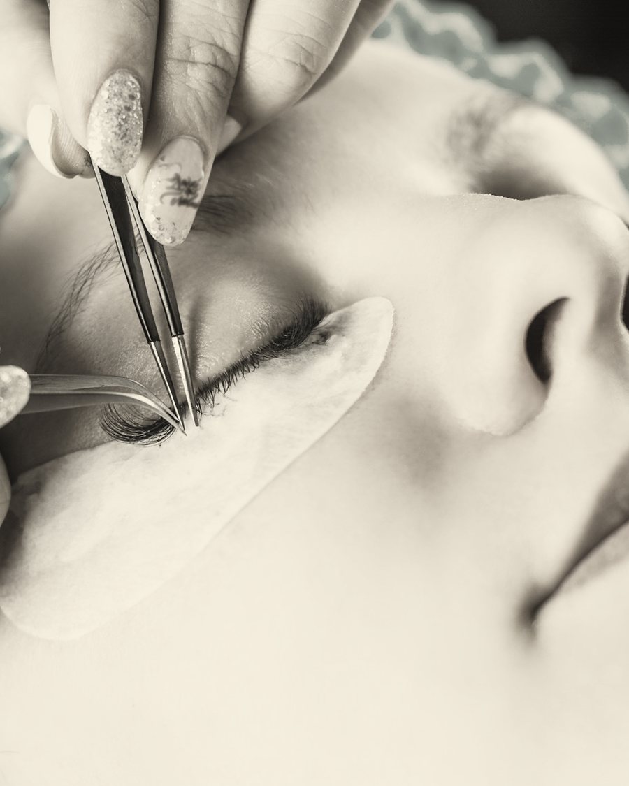 An artist placing a single lash extension with fine tweezers