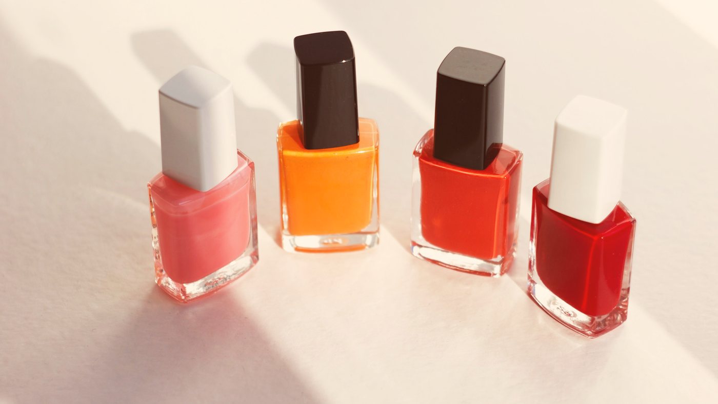 A row of nail polish bottles from pale pink to cherry red, in soft daylight