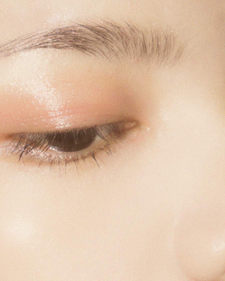 Close-up of a closed eye with soft peach eyeshadow and groomed brows