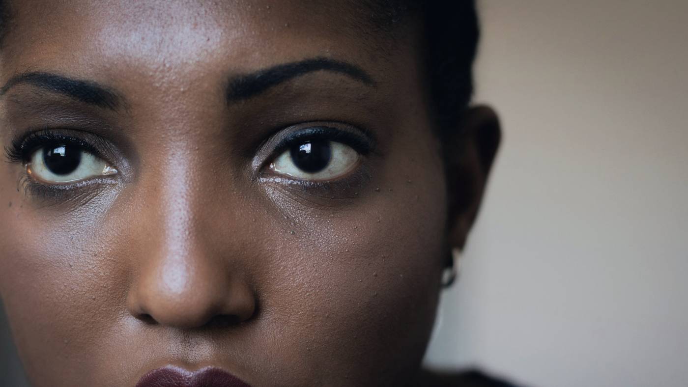 Close-up portrait of a woman with deep brown skin looking straight at the camera