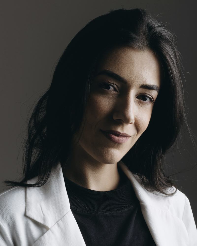 Portrait of Dr Imogen Odell in a white coat against a dark backdrop