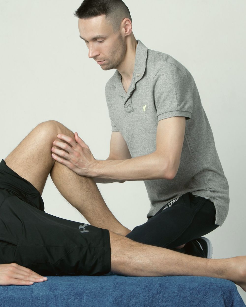 Physiotherapist assessing a patient's knee on a treatment couch
