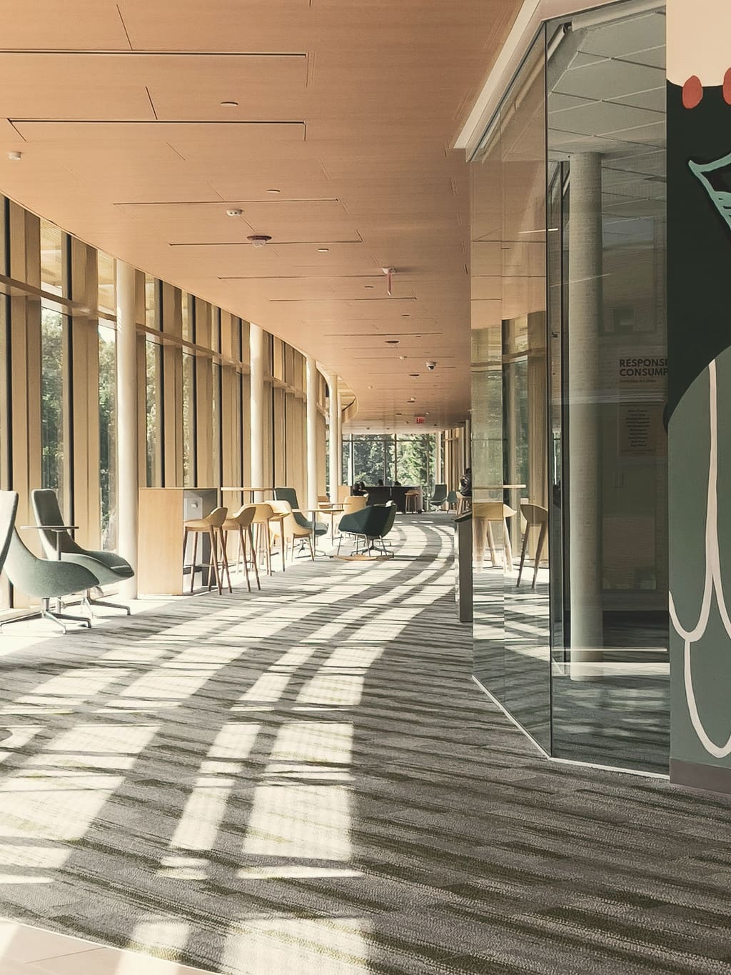 A long sunlit corridor with chairs and striped shadows on the floor