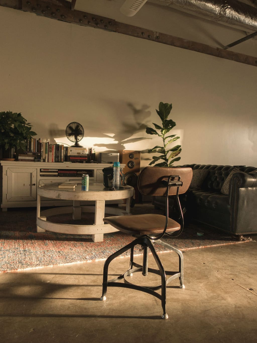 A warm lounge with a leather sofa, a round table, books and plants