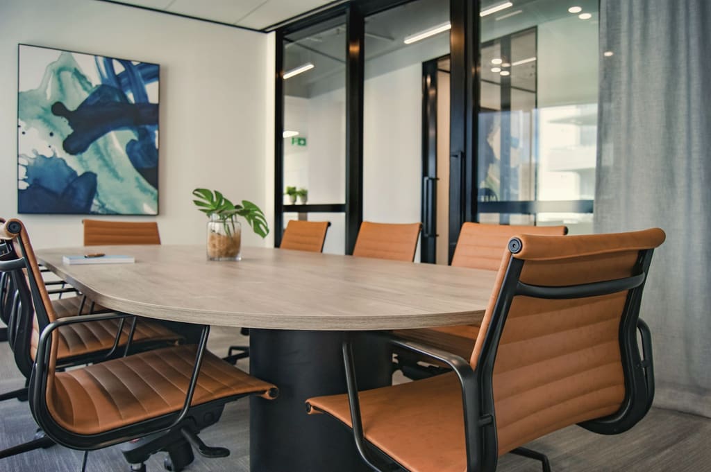 Oval meeting table with tan leather chairs and a large abstract painting