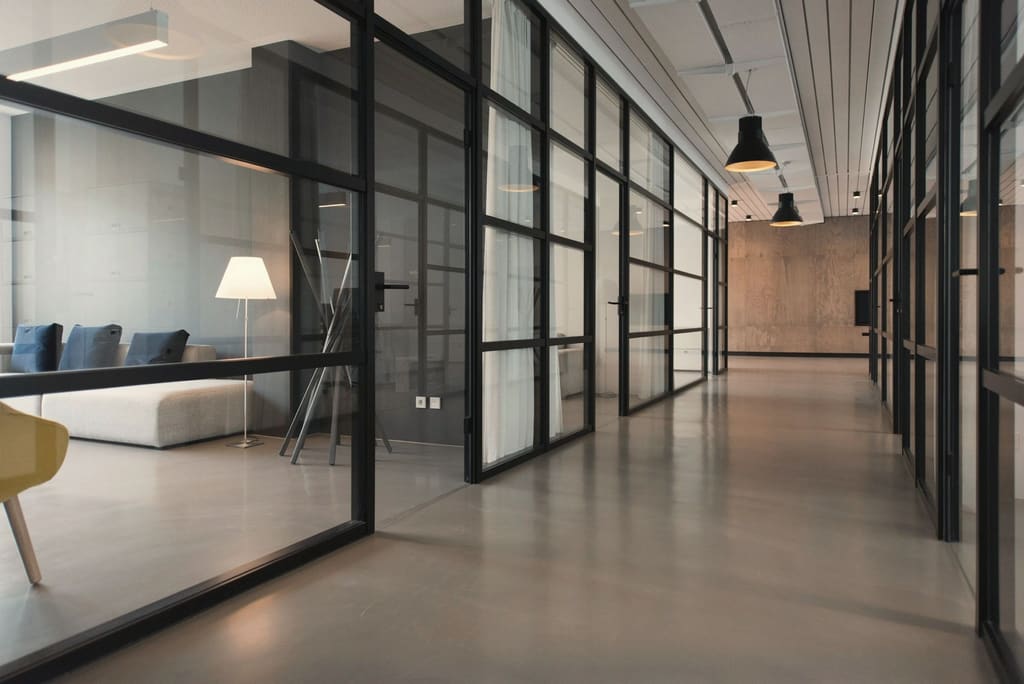 A corridor of glass-walled private offices with black steel frames