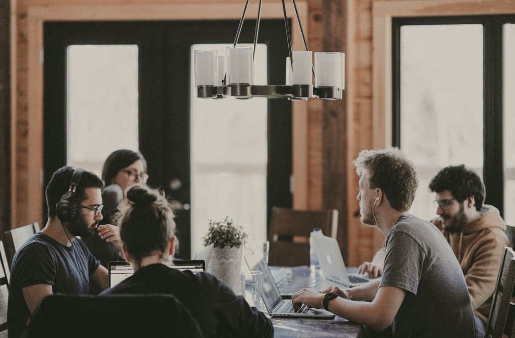 A small group working around a wooden table under a pendant light