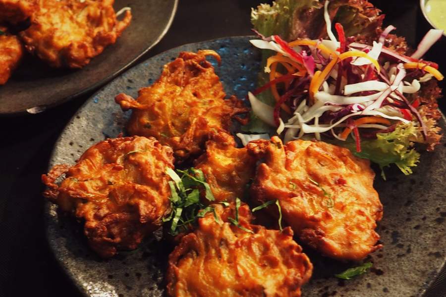 Onion bhajis on a dark plate with shredded salad