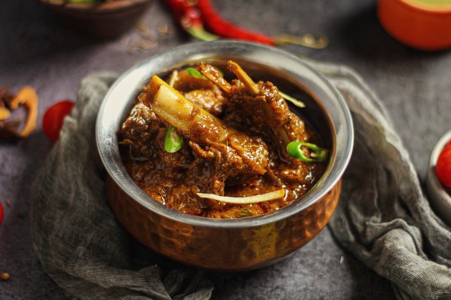 Slow-cooked lamb curry on the bone in a steel bowl