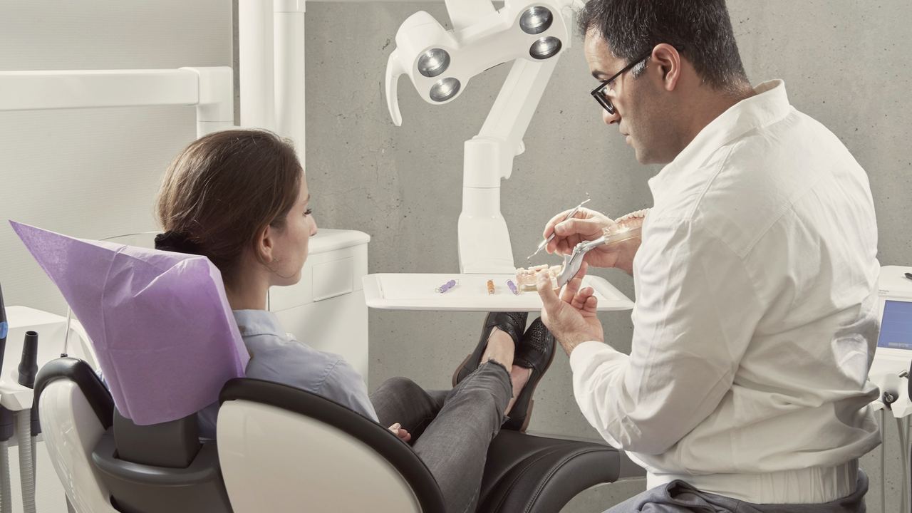 A dentist working on a relaxed patient who is lying back in the chair