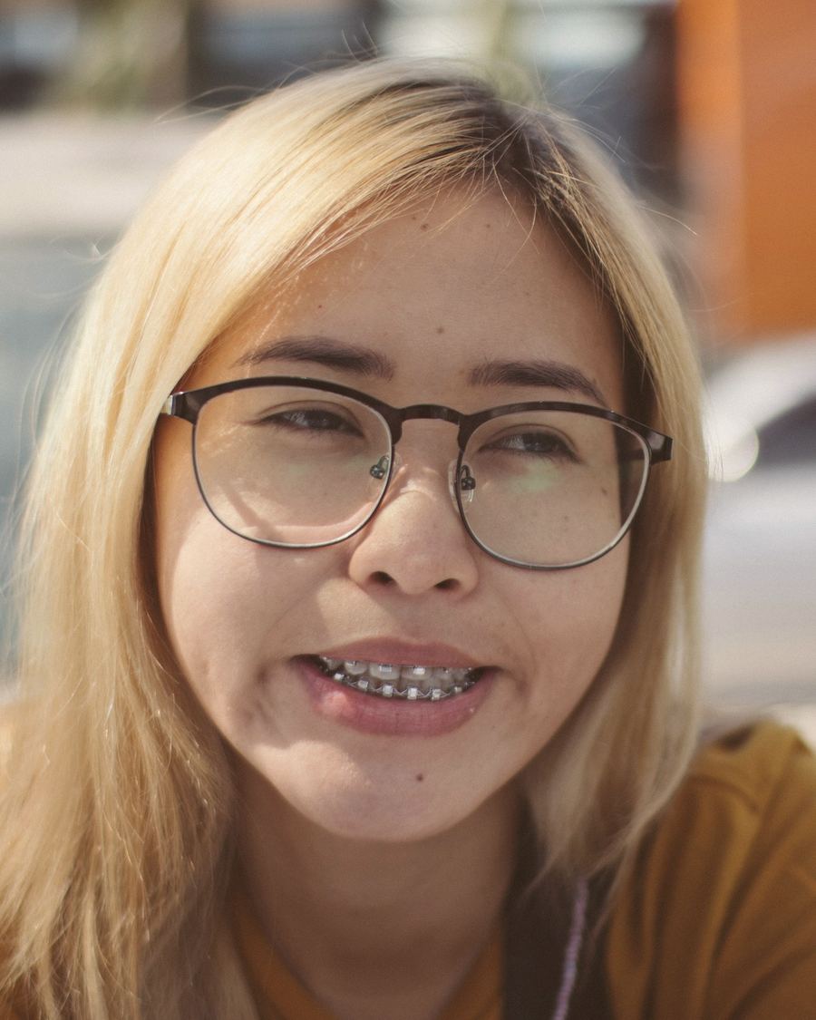 A teenager in glasses smiling to show her braces