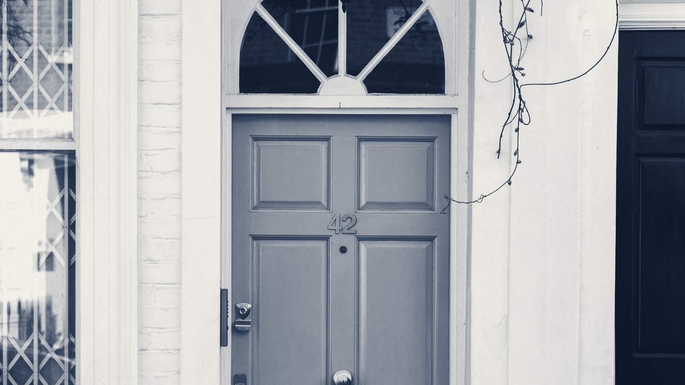 A pale Georgian front door with a fanlight, set in a white-painted mews house