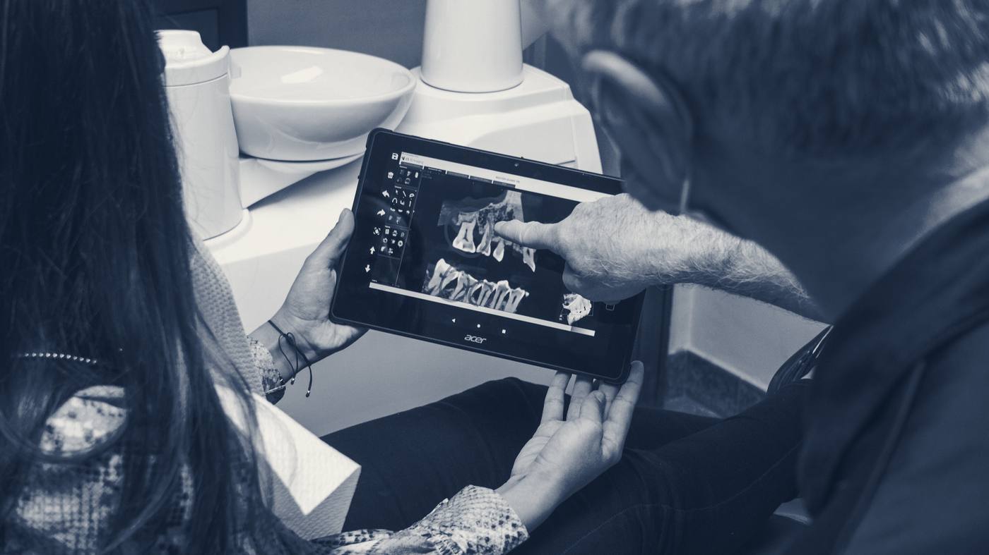 A clinician shows a patient her 3D dental scan on a tablet