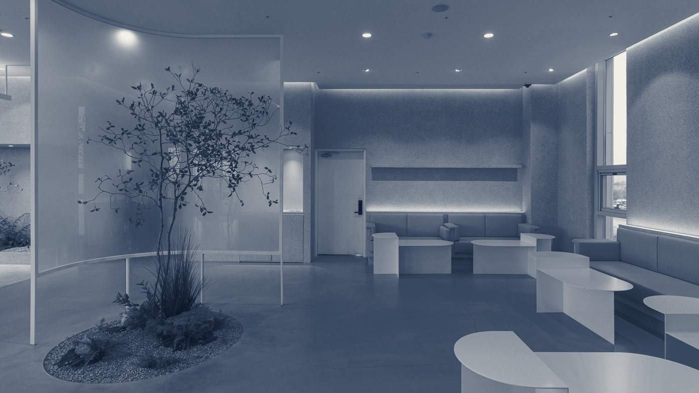 A calm white reception with a small tree growing from a planted island and low built-in seating