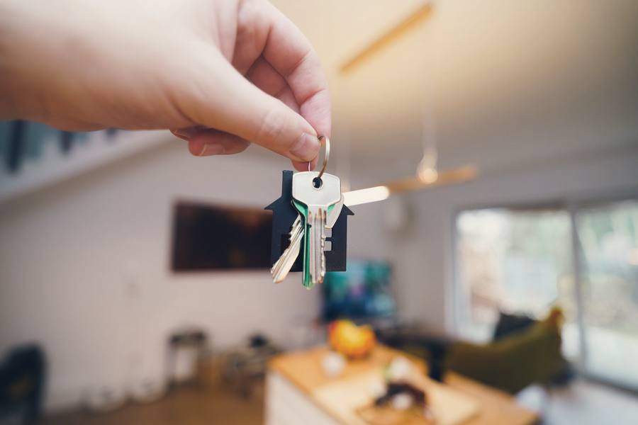 A hand holding a set of house keys in a softly lit living room