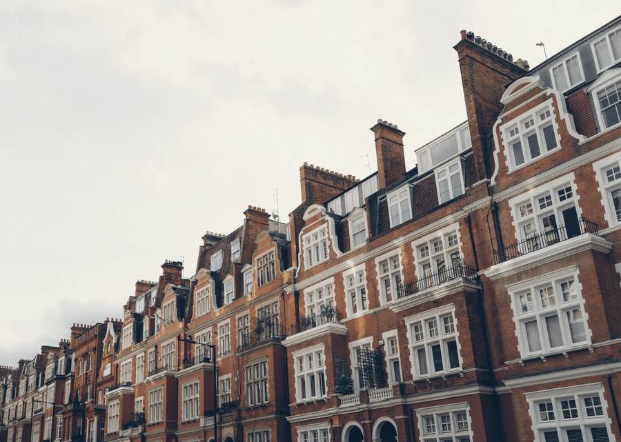 A long red-brick Edwardian mansion block with white window frames and tall chimneys