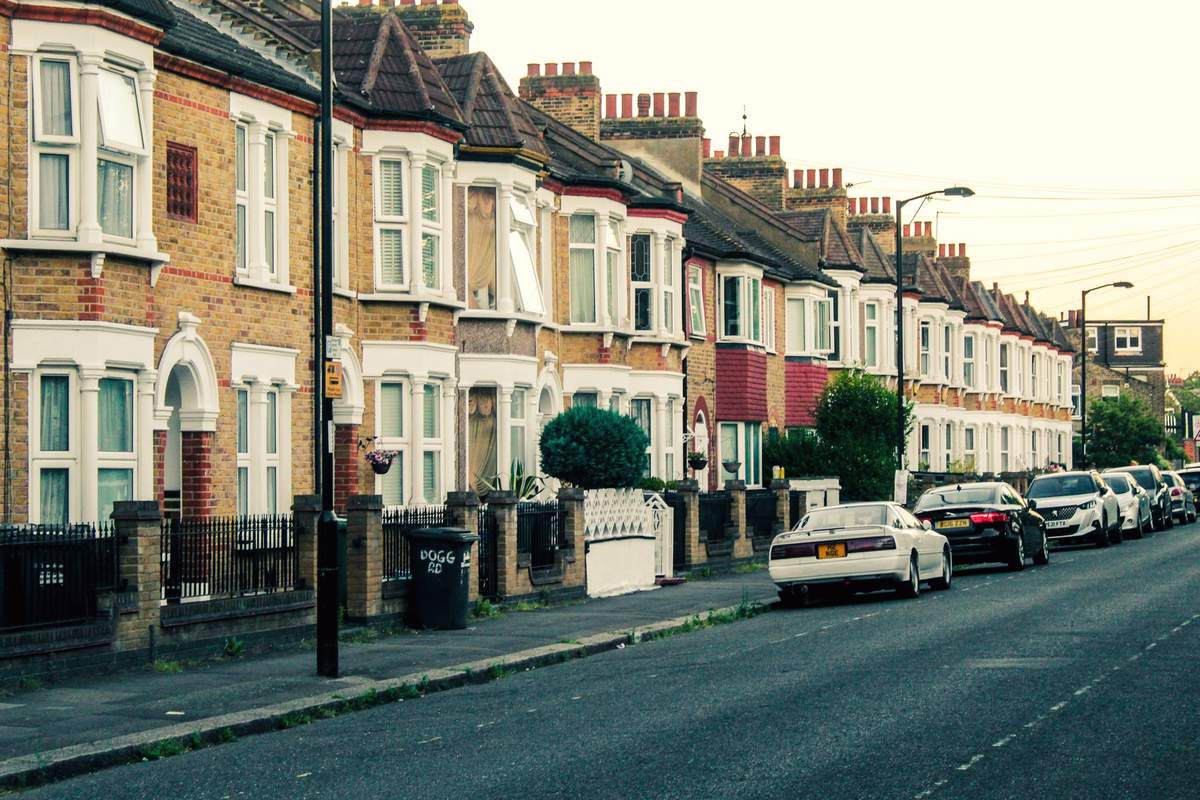A row of Victorian terraced houses with bay windows on a quiet south London street in evening light