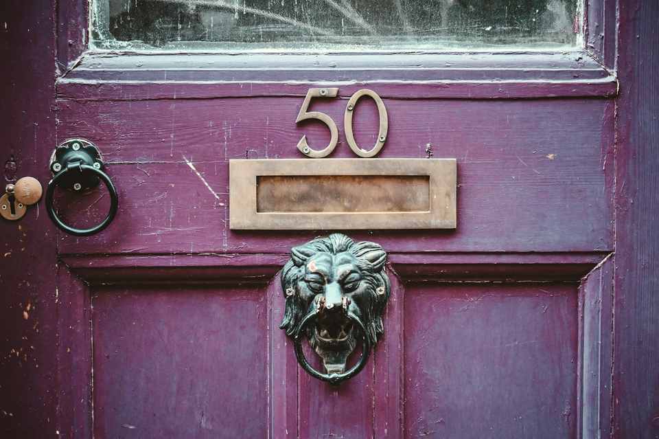 A lacquered aubergine front door with a brass lion knocker