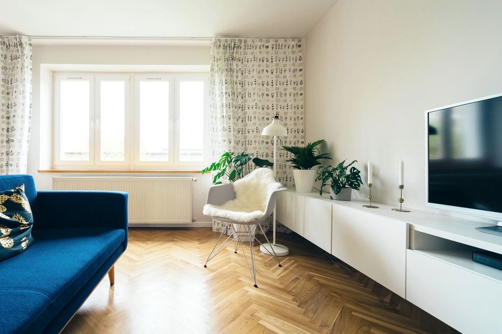 A bright, empty-feeling living room with herringbone floors after a move-out clean