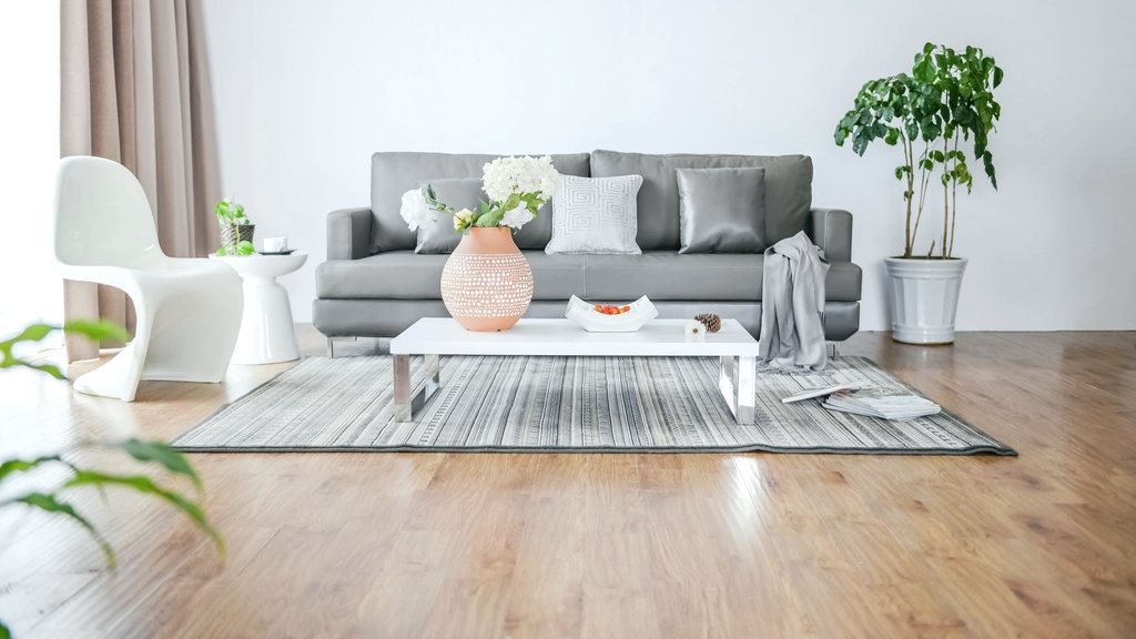 A tidy, sunlit living room with a grey sofa and plants