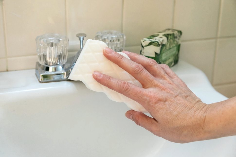 A hand polishing a bathroom basin
