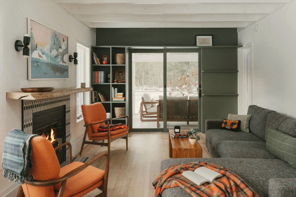 A living room with a fireplace, armchairs and garden doors