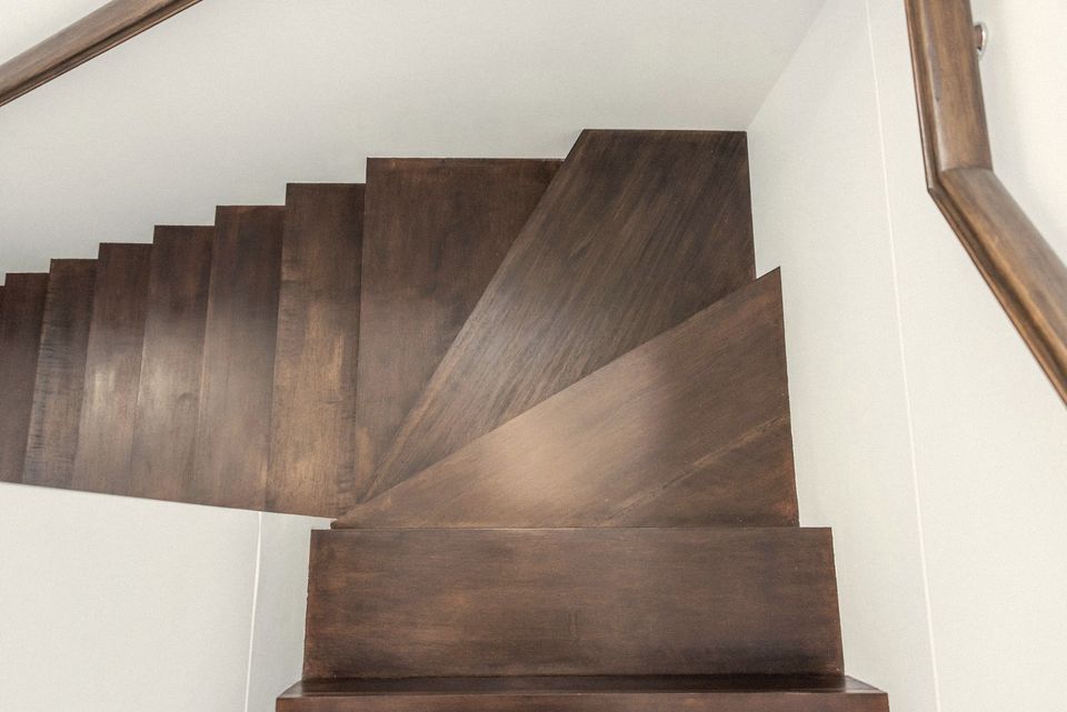 A turning timber staircase against white walls