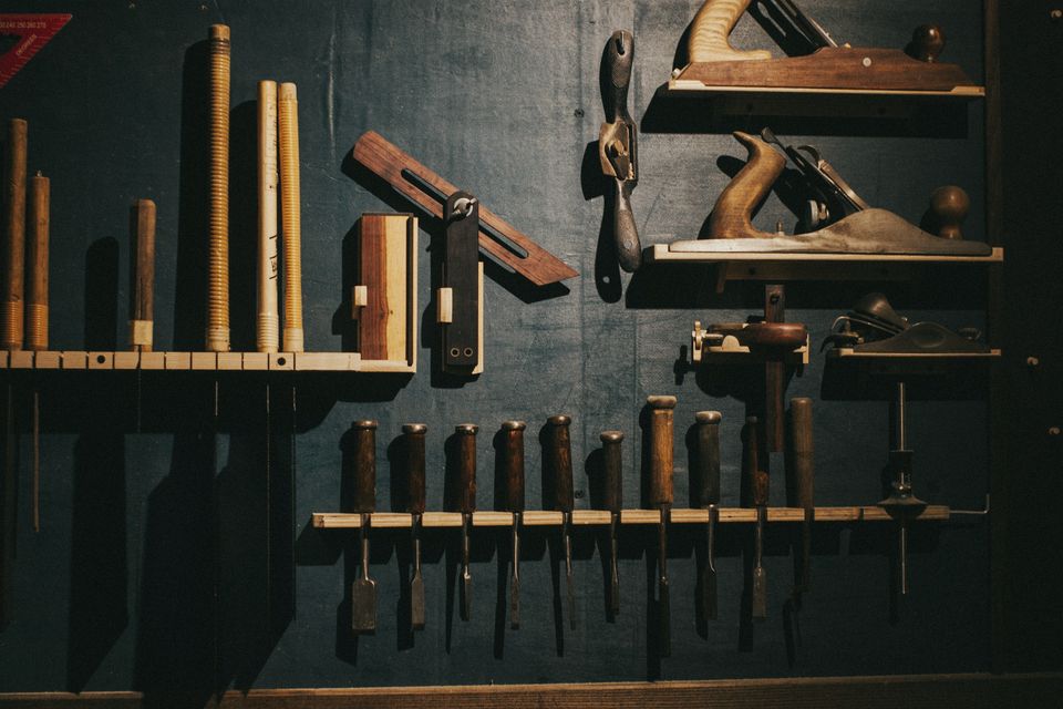 Woodworking hand tools arranged on a dark workshop wall