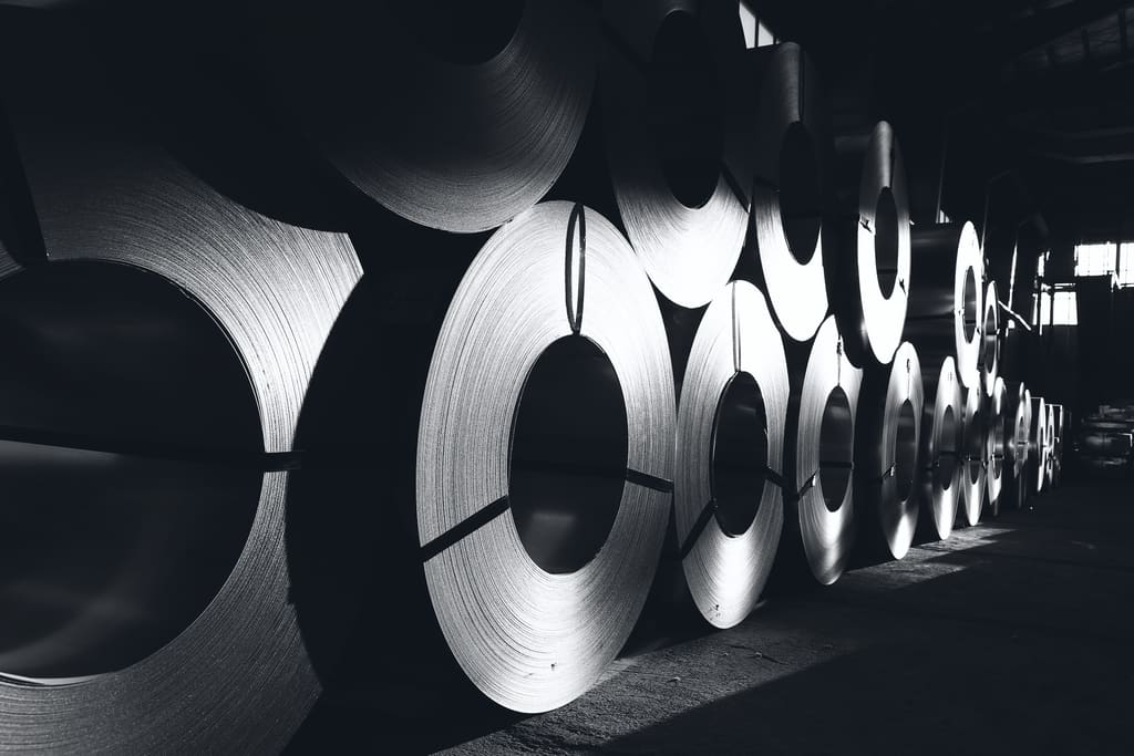Rolled steel coils lined up in a dim warehouse