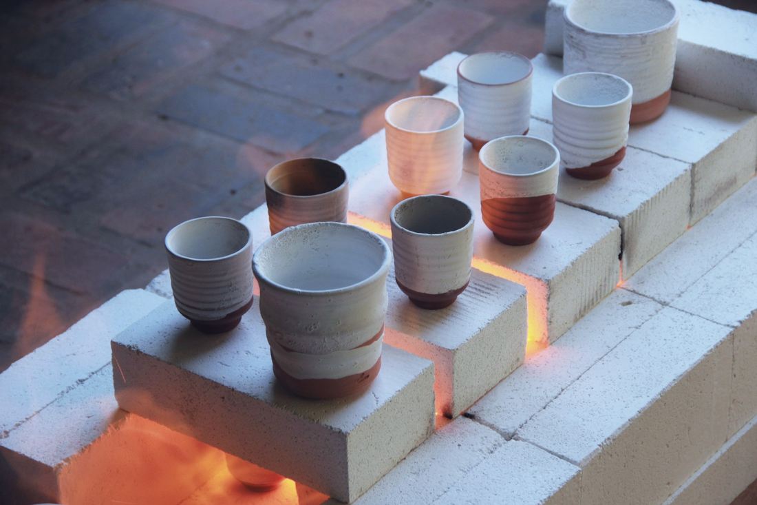 Small stoneware cups glowing on the shelves of an opened kiln