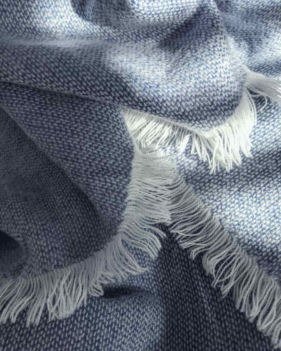 A blue-grey merino throw with a fringed edge