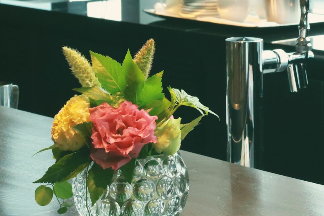 A small posy of pink and yellow flowers in a cut-glass bowl on a dark bar counter