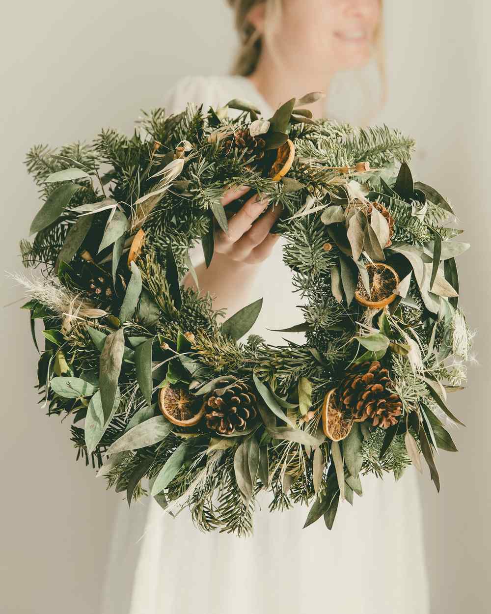 A woman holding a finished dried-leaf wreath
