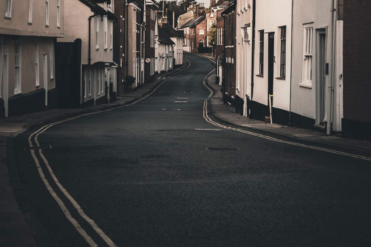 A curving street of white and brick houses at first light