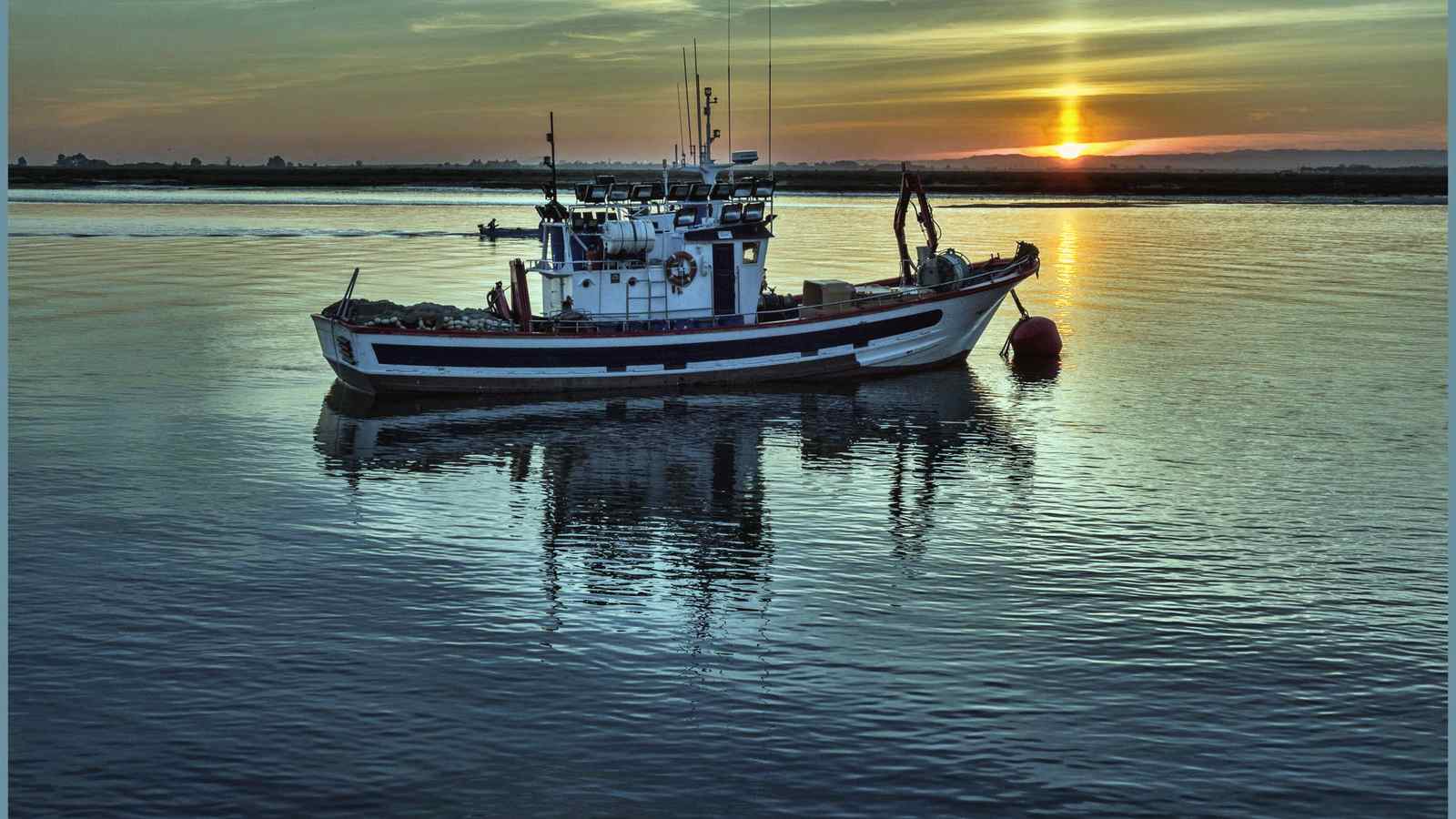 A small fishing boat on calm water at sunset