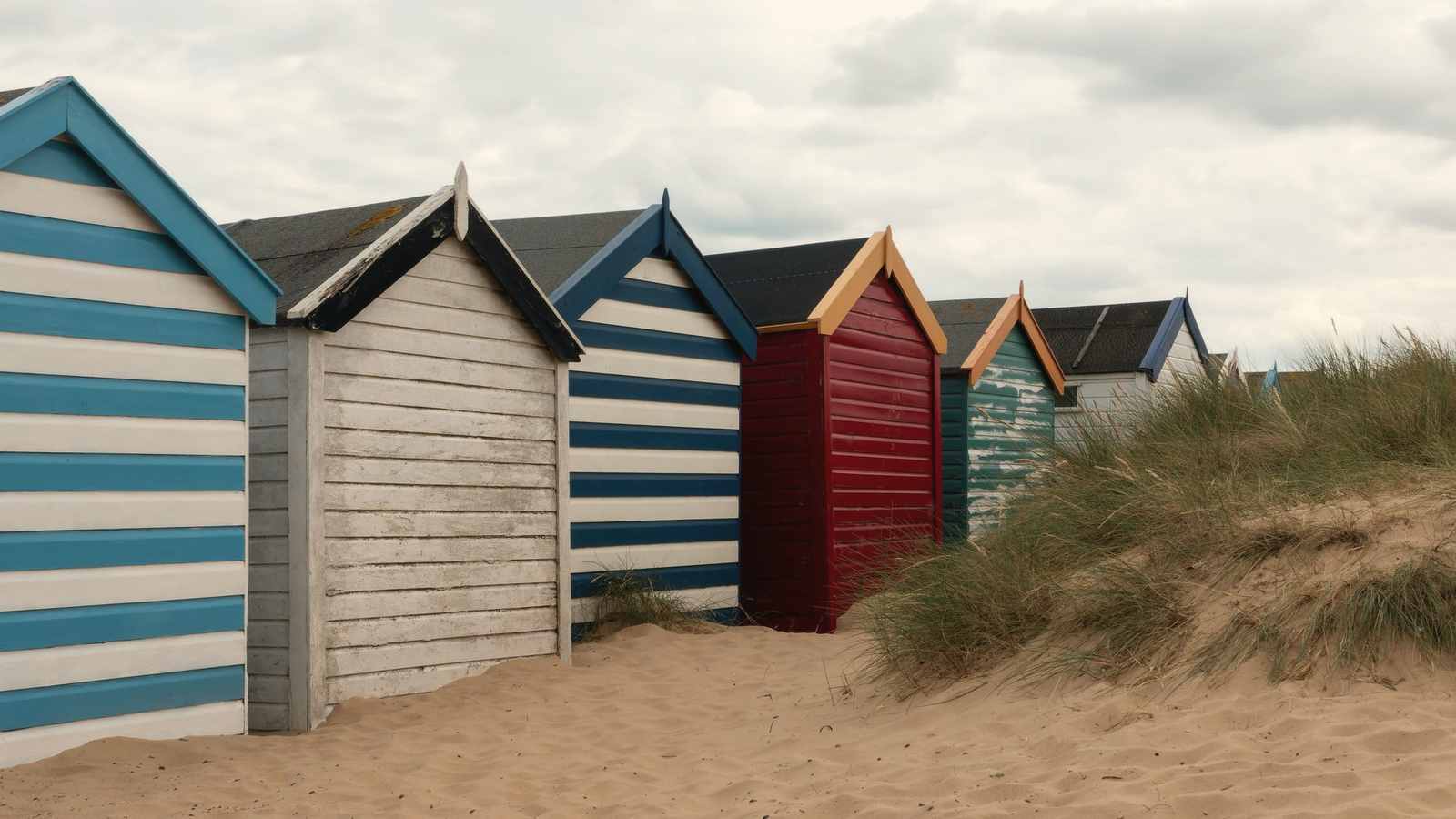 Striped beach huts on a sandy shore