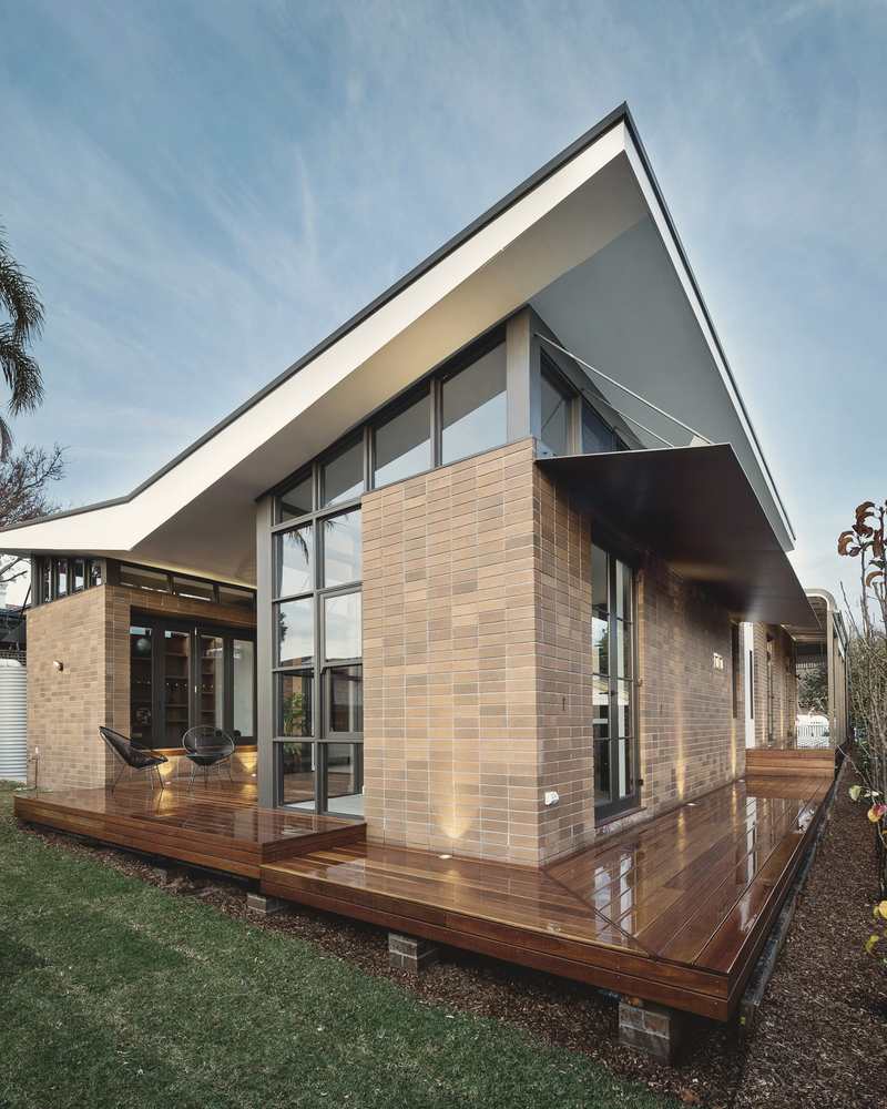 Modern rear extension with brick and full-height glazing opening onto a timber deck