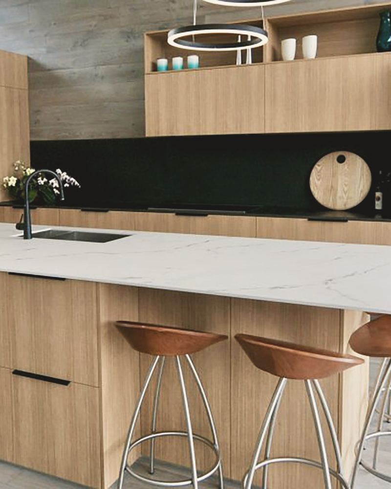 Oak kitchen with a white stone island and three bar stools
