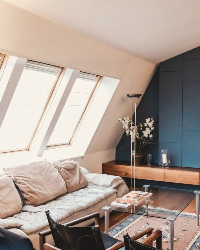 Converted loft living room with three roof windows, a deep blue wall and a timber sideboard